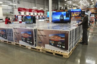 In this Nov. 10, 2020 photo, a shopper stands by a display of Samsung 65-inch televisions in a Costco warehouse in Sheridan, Colo.  U.S. consumer confidence posted a gain in January, helped by a rise in expectations about the future. The Conference Board reported Tuesday, Jan. 26, 2021, that its consumer confidence index increased to 89.3, a rebound from December when it had fallen to a reading of 87.1.  (AP Photo/David Zalubowski)