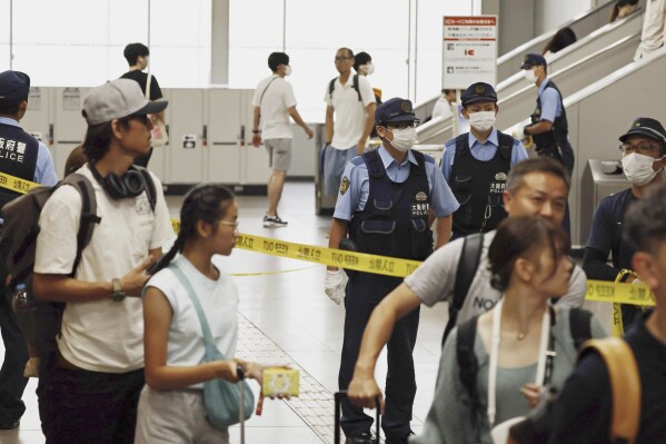 Japanese police officers patrol a train station after a man was arrested at the station in Izumisano, south of Osaka, western Japan, Monday, July 24, 2023, following an emergency call of a knife attack on a train. Japanese police said Monday that they have arrested a man on suspicion of slashing multiple people on a train in western Japan. (Kenzaburo Fukuhara/Kyodo News via AP)