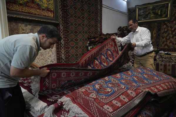 Carpet sellers adjust carpets in their shop in northern Tehran, Iran, Monday, June 2, 2025. (AP Photo/Vahid Salemi)