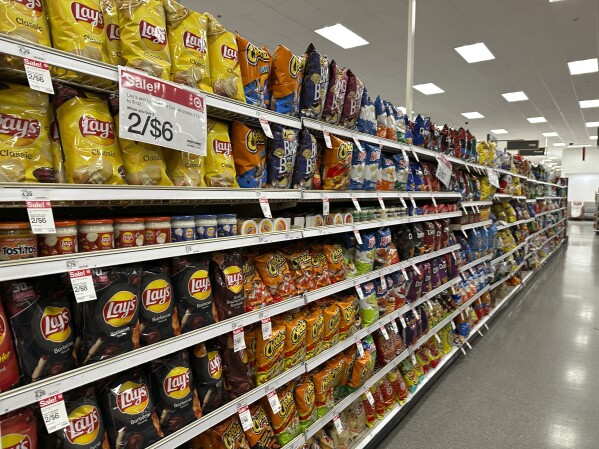 FILE - Sale signs hang on the long display of snacks at a Target store Oct. 4, 2023, in Sheridan, Colo. Target plans on cutting prices on thousands of consumer basics this summer, goods ranging from diapers to milk, with more Americans paying closer attention to their spending as inflation cuts into household budgets.(AP Photo/David Zalubowski, File)