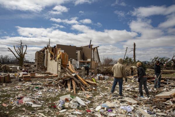 Family and neighbors look through debris on Ed Whestine's farm southwest of Wellman, Iowa on Saturday, April 1, 2023. Storms that dropped possibly dozens of tornadoes killed multiple people in small towns and big cities across the South and Midwest, tearing a path through the Arkansas capital, collapsing the roof of a packed concert venue in Illinois, and stunning people throughout the region Saturday with the damage's scope. (Nick Rohlman/The Gazette via AP)