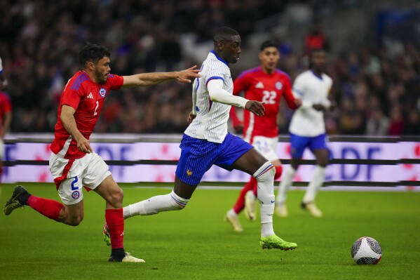 France's Randal Kolo Muani, right, is challenged by Chile's Gabriel Suazo during an international friendly soccer match between France and Chile at the Orange Velodrome stadium in Marseille, southern France, Tuesday, March 26, 2024. (AP Photo/Daniel Cole)