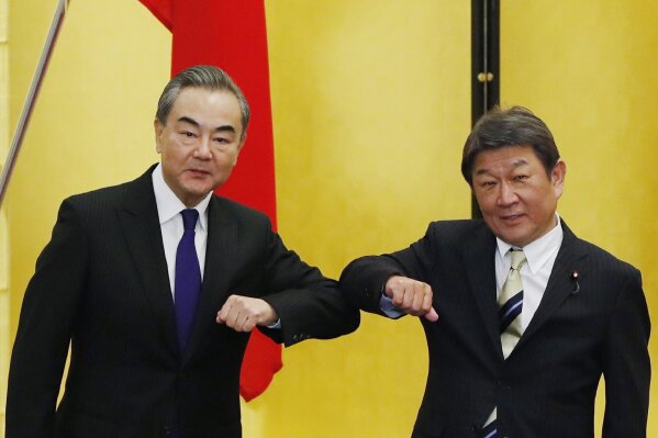 FILE - In this Nov. 24, 2020, file photo, Chinese Foreign Minister Wang Yi, left, and his Japanese counterpart Toshimitsu Motegi bump elbows as they meet amid the coronavirus outbreak, in Tokyo. Wang has cautioned Japan against teaming up with the U.S. to counter China, ahead of a U.S.-Japan summit on April 16, 2021. Wang said that Japan should not be misled by countries holding a biased view against China. He made the remarks in a phone conversation Monday evening, April 5, 2021 with Motegi. (Issei Kato/Pool Photo via AP, File)