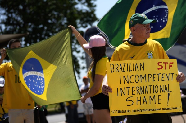 Supporters of former President Jair Bolsonaro hold up posters and flags in support of a proposed bill to grant amnesty to those arrested for storming government buildings in an alleged coup attempt in 2023, in Brasilia, Brazil, Sunday, March 16, 2025. (AP Photo/Eraldo Peres)