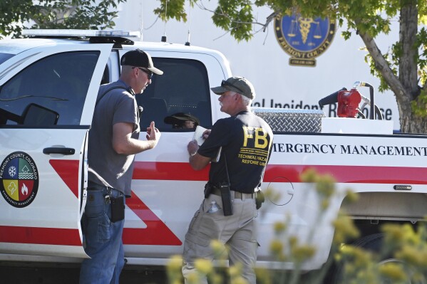Agents from the FBI and Fremont County Emergency Management Office confer at the scene of the Return to Nature Funeral Home on Monday, Oct. 9, 2023, where over 100 decomposing bodies were found last week in Penrose, Colo. (Jerilee Bennett/The Gazette via AP)