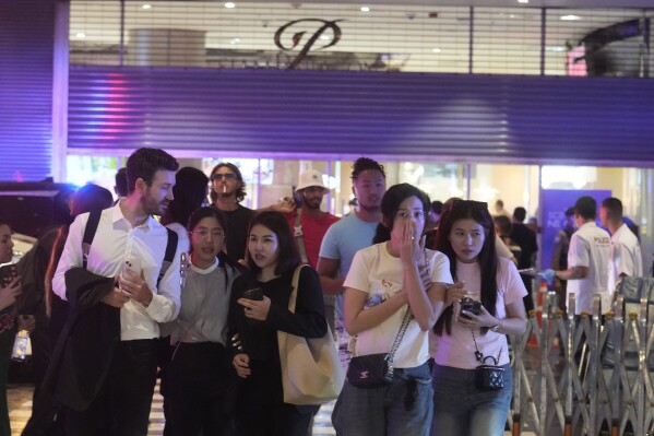 Visitors evacuate from a shopping mall in Bangkok, Thailand, Tuesday, Oct. 3, 2023. Hundreds of shoppers fled the major shopping mall in the center of the Thai capital Bangkok on Tuesday afternoon after what sounded like gunshots were heard inside. (AP Photo/Sakchai Lalit)