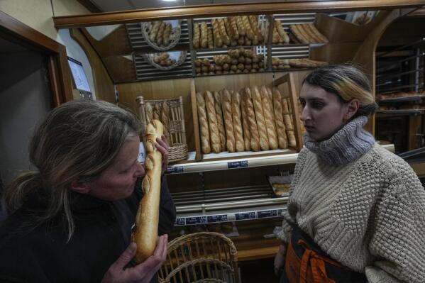 Bakery owner Florence Poirier, LEFT, smells the fresh baguette who comes out of the oven as Mylene Poirier stands next to her at a bakery, in Versailles, west of Paris, Tuesday, Nov. 29, 2022. The humble baguette -- the crunchy ambassador for French baking around the world -- is being added to the U.N.'s list of intangible cultural heritage as a cherished tradition to be preserved by humanity. UNESCO experts gathering Wednesday Nov. 30, 2022 in Morocco decided that the simple French flute deserved U.N. recognition. (AP Photo/Michel Euler)