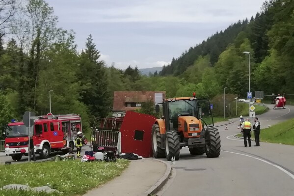 Rescue workers stand next to an overturned May wagon after an accident in Kandern, Germany, Wednesday, May 1, 2024. Police say an accident involving a trailer in southwestern Germany has left 30 people injured, 10 of them seriously. German news agency dpa reported that the accident happened near the city of Freiburg on Wednesday. (Gudrun Gehr, Oberbadisches Verlagshaus/dpa via AP)