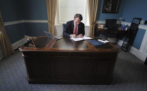 FILE - Virginia Gov. Glenn Youngkin works at his desk inside his private office at the State Capitol in Richmond, Va., Jan. 18, 2022. Youngkin has used his first two weeks in office to push Virginia firmly to the right, attempting a dramatic political shift in a state once considered reliably Democratic that's being closely watched by others in the GOP. (Bob Brown/Richmond Times-Dispatch via AP, File)