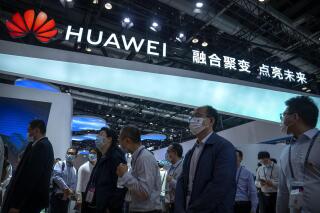 Visitors walk past a booth for Chinese technology firm Huawei at the PT Expo in Beijing on Sept. 28, 2021. Chinese tech giant Huawei's revenue rose in the latest quarter as infrastructure sales helped to offset damage to its smartphone business under U.S. sanctions, according to figures released Thursday, Oct. 27, 2022. (AP Photo/Mark Schiefelbein)