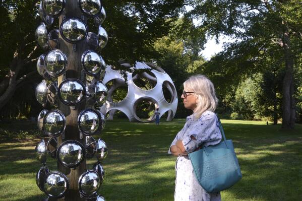 Doris Brautigan looks at Marko Remec's "Would That I Wish For, (Tall Totem)," made of wood, acrylic steel convex dome mirrors, on display at LongHouse Reserve, Friday, Sept. 9, 2022, in East Hampton, N.Y. The 16-acre sculpture garden, museum and nature reserve was founded by the late textile designer and collector Jack Lenor Larsen. (AP Photo/Pamela Hassell)