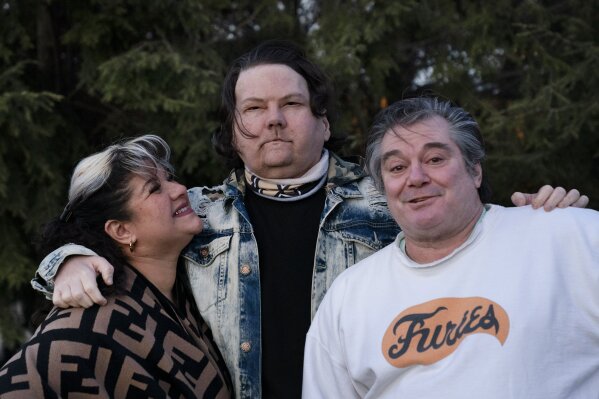 Joe DiMeo stands with his parents Rose and John in the backyard of their home in Clark, N.J., Thursday, Jan. 28, 2021, six months after an extremely rare double hand and face transplant. “In the future, I have a lot more plans for myself,” he said. “You got a new chance at life. You really can’t give up.” (AP Photo/Mark Lennihan)