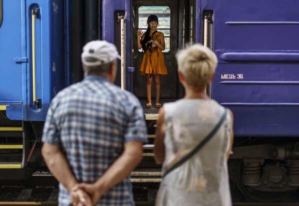 A young girl holds her dog while waving goodbye to her grandparents from an evacuation train departing Pokrovsk, Donetsk region, eastern Ukraine, Tuesday, Aug. 2, 2022, for a safer part of the country to the west. (AP Photo/David Goldman)