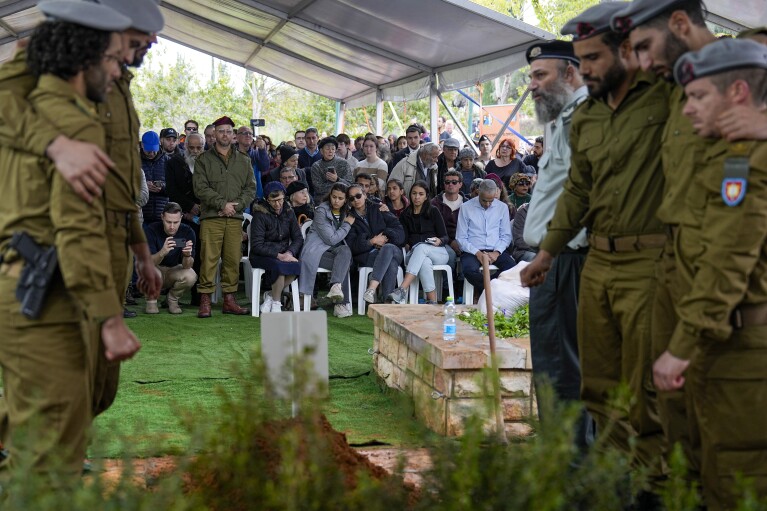 Mourners and Israeli soldiers gather in grief around the grave of Israeli reserve solider Sergeant major Eliran Yeger during his funeral in Kiryat Shaul military cemetery in Tel Aviv, Israel, Sunday, Jan. 28, 2024. U.S. and Mideast mediators appeared optimistic in recent days that they are closing in on a deal for a two-month cease-fire in Gaza and the release of over 100 hostages held by Hamas. But on Tuesday, Israeli Prime Minister Benjamin Netanyahu rejected the militant group's two main demands — that Israel withdraw its forces from Gaza and release thousands of Palestinian prisoners — indicating that the gap between the two sides remains wide. (AP Photo/Ariel Schalit)