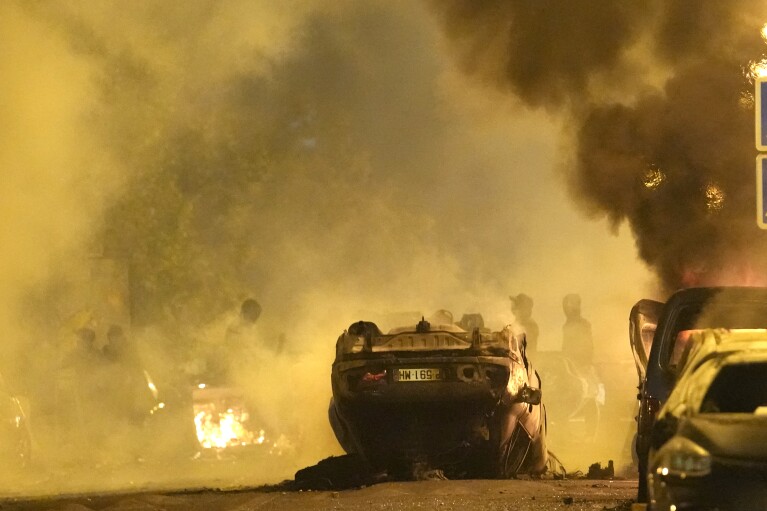 Youths clash with Police forces as cars burn in Nanterre, outside Paris, Thursday, June 29, 2023. The death of 17-year-old Nael by police during a traffic check Tuesday in the Paris suburb of Nanterre elicited nationwide concern and widespread messages of indignation and condolences. Interior Minister Gerald Darmanin said 1,200 police were deployed overnight and 2,000 would be out in force Wednesday in the Paris region and around other big cities to "maintain order."(AP Photo/Christophe Ena)