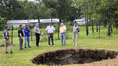 This photo provided by Hillsborough County, Fla., shows a sinkhole that in 2013 fatally swallowed a man sleeping in his own house. The sinkhole has reopened for a third time, this time behind chain-link fencing and doing no harm to people or property. Hillsborough County officials said the sinkhole located in the Tampa suburb of Seffner, Fla., appeared again on Monday, July 10, 2023, which they said is not unusual for such underground formations especially in central Florida with its porous limestone base. (Todd Pratt/Hillsborough County via AP)