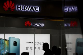 FILE - In this May 29, 2019 file photo, a man walks past a Huawei retail store in Beijing. On Friday, June 21, 2019, the United States blacklisted five Chinese organizations, calling them national security threats and cutting them off from critical U.S. technology. In May, the U.S. Commerce Department blacklisted telecommunications giant Huawei, heightening tensions with Beijing. (AP Photo/Andy Wong)