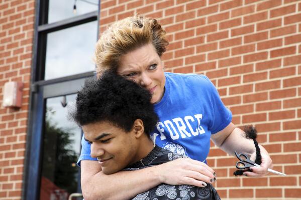 In this Saturday, May 29, 2021, photo, provided by Gregg Gelmis, Kelly Moïse hugs her son Kieran after cutting the last braid from his hair during a live donation fundraiser, "Kieran's Curls for Cancer," for the nonprofit Children with Hair Loss in Huntsville, Ala. So far, they've raised $35,000. (Courtesy of Gregg Gelmis via AP)