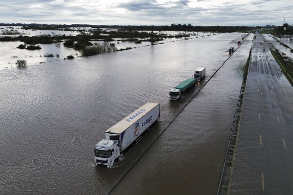 Semi-trucks drive through a flooded highway after heavy rains in Campana, Argentina, Saturday, May 17, 2025. (AP Photo/Rodrigo Abd)