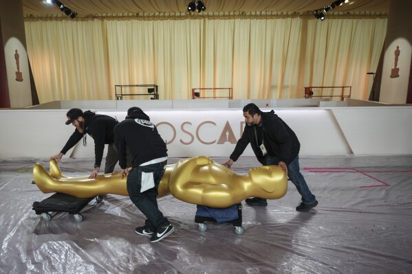 Workers move an Oscar statue through the red carpet area before the 97th Academy Awards in Los Angeles, Saturday, March 1, 2025. (AP Photo/Jae C. Hong)
