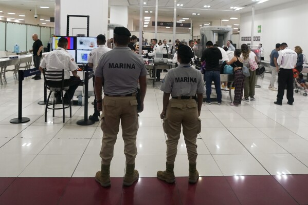 FILE - Mexican Navy officers stand guard next to a security checkpoint at the Benito Juarez International Airport, in Mexico City, Friday, June 30, 2023. Mexico's armed forces are taking control of the capital's main airport and the government plans to give the military control of nearly a dozen more across the country as the president aims at corruption and mismanagement. (AP Photo/Fernando Llano, File)
