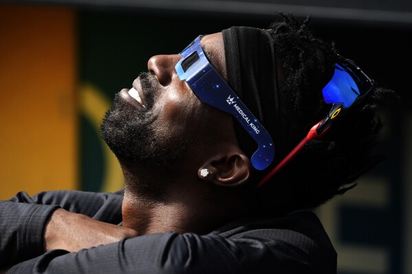 Pittsburgh Pirates' Andrew McCutchen views the solar eclipse before a baseball game against the Detroit Tigers in Pittsburgh, Monday, April 8, 2024. (AP Photo/Gene J. Puskar)