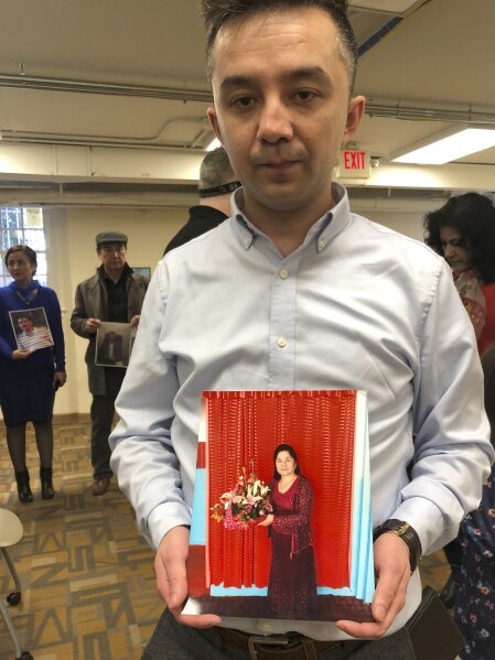 FILE - In this file photo taken Sunday, Feb. 24, 2019, Ferkat Jawdat holds up a photo of his mother during a gathering to raise awareness about loved ones who have disappeared in China's far west Xinjiang region in Washington DC. The accusation of genocide by U.S. Secretary of State Mike Pompeo against China touches on a hot-button human rights issue between China and the West. (AP Photo/Christina Larson, File)