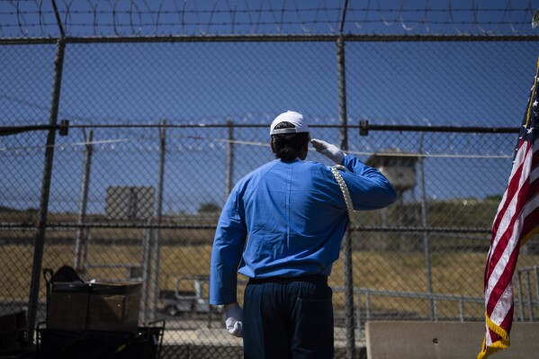 Incarcerated graduate Gerald Massey, who earned his bachelor's degree in communications through the Transforming Outcomes Project at Sacramento State, salutes a U.S. flag during his graduation ceremony at Folsom State Prison in Folsom, Calif., Thursday, May 25, 2023. (AP Photo/Jae C. Hong)