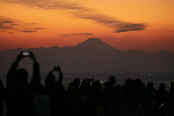 FILE - I visitatori scattano foto del Monte Fuji dallo Shibuya Sky Observation Deck lunedì 20 gennaio 2020, nel quartiere Shibuya di Tokyo.  (AP Photo/Jay C. Hong, file)