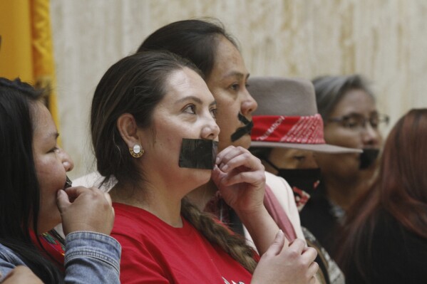 FILE - Protesters place tape over their mouths to express frustration with the appointment of James Mountain to lead the New Mexico Indian Affairs Department at the New Mexico state Capitol building in Santa Fe, N.M., on Friday, March 17, 2023. Mountain is leaving that post less than a year into the job to take on a new role as a policy adviser to the governor. Mountain's new role as senior policy adviser for tribal affairs was confirmed Friday, Dec. 15, by the governor's office in a statement. (AP Photo/Morgan Lee, File)