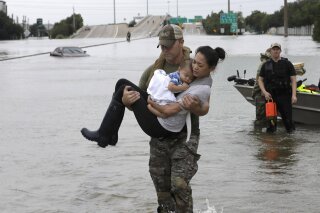 
              CORRECTS FROM CONNIE TO CATHERINE - Houston Police SWAT officer Daryl Hudeck carries Catherine Pham and her 13-month-old son Aiden after rescuing them from their home surrounded by floodwaters from Tropical Storm Harvey Sunday, Aug. 27, 2017, in Houston. The remnants of Hurricane Harvey sent devastating floods pouring into Houston Sunday as rising water chased thousands of people to rooftops or higher ground. (AP Photo/David J. Phillip)
            