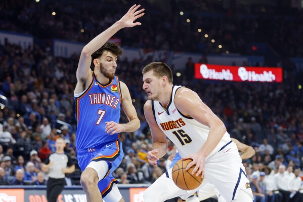 Denver Nuggets center Nikola Jokic (15) drives against Oklahoma City Thunder forward Chet Holmgren (7) in the first half of an NBA basketball game, Sunday, Oct. 29, 2023, in Oklahoma City. (AP Photo/Nate Billings)