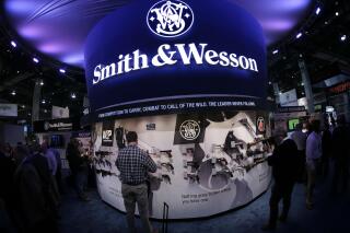 FILE - In this Tuesday, Jan. 14, 2014 file photo, trade show attendees examine handguns and rifles at the Smith & Wesson display booth at the Shooting Hunting and Outdoor Trade Show, in Las Vegas. Smith & Wesson announced Thursday, Sept. 30, 2021, it plans to move its headquarters from Massachusetts to Tennessee. (AP Photo/Julie Jacobson, File)