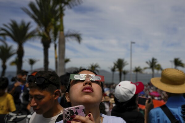 People use special glasses to watch a total solar eclipse in Mazatlan, Mexico, Monday, April 8, 2023. (AP Photo/Fernando Llano)
