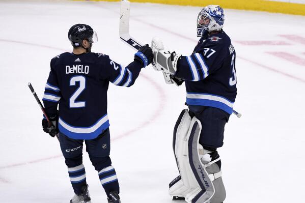 Winnipeg Jets' Dylan DeMelo (2) celebrates with goaltender Connor Hellebuyck (37) after defeating the Dallas Stars in an NHL hockey game, Tuesday, Nov. 8, 2022 in Winnipeg, Manitoba. (Fred Greenslade/The Canadian Press via AP)