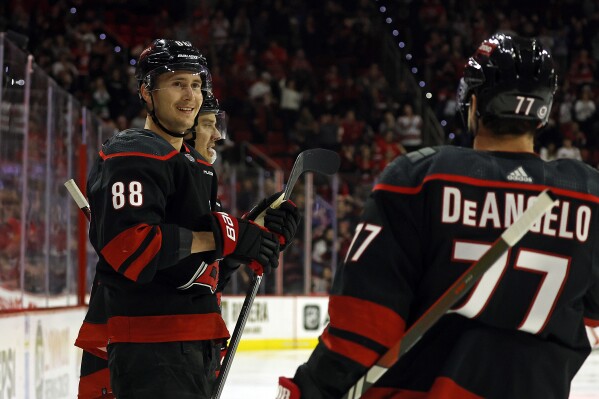 Carolina Hurricanes' Martin Necas celebrates his goal with teammates Sebastian Aho (20) and Tony DeAngelo during the second period of an NHL hockey game against the Chicago Blackhawks in Raleigh, N.C., Monday, Feb. 19, 2024. (AP Photo/Karl B DeBlaker)