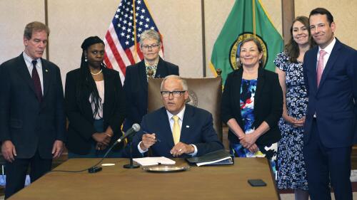 Gov. Jay Inslee signs Senate Bill 5536 concerning controlled substances on Tuesday, May 16, 2023, in Olympia, Wash. Behind him are from left to right: Rep. Roger Goodman, D- Kirkland, Rep. Jamila Taylor, D-Federal Way, House Speaker Laurie Jinkins, D-Tacoma, June Robinson, D-Everett, an identified woman and Andy Billig, D-Spokane. The policy, approved by Washinton lawmakers and signed by Inslee, keeps controlled substances illegal while boosting resources to help those struggling with addiction. (Karen Ducey/The Seattle Times via AP)