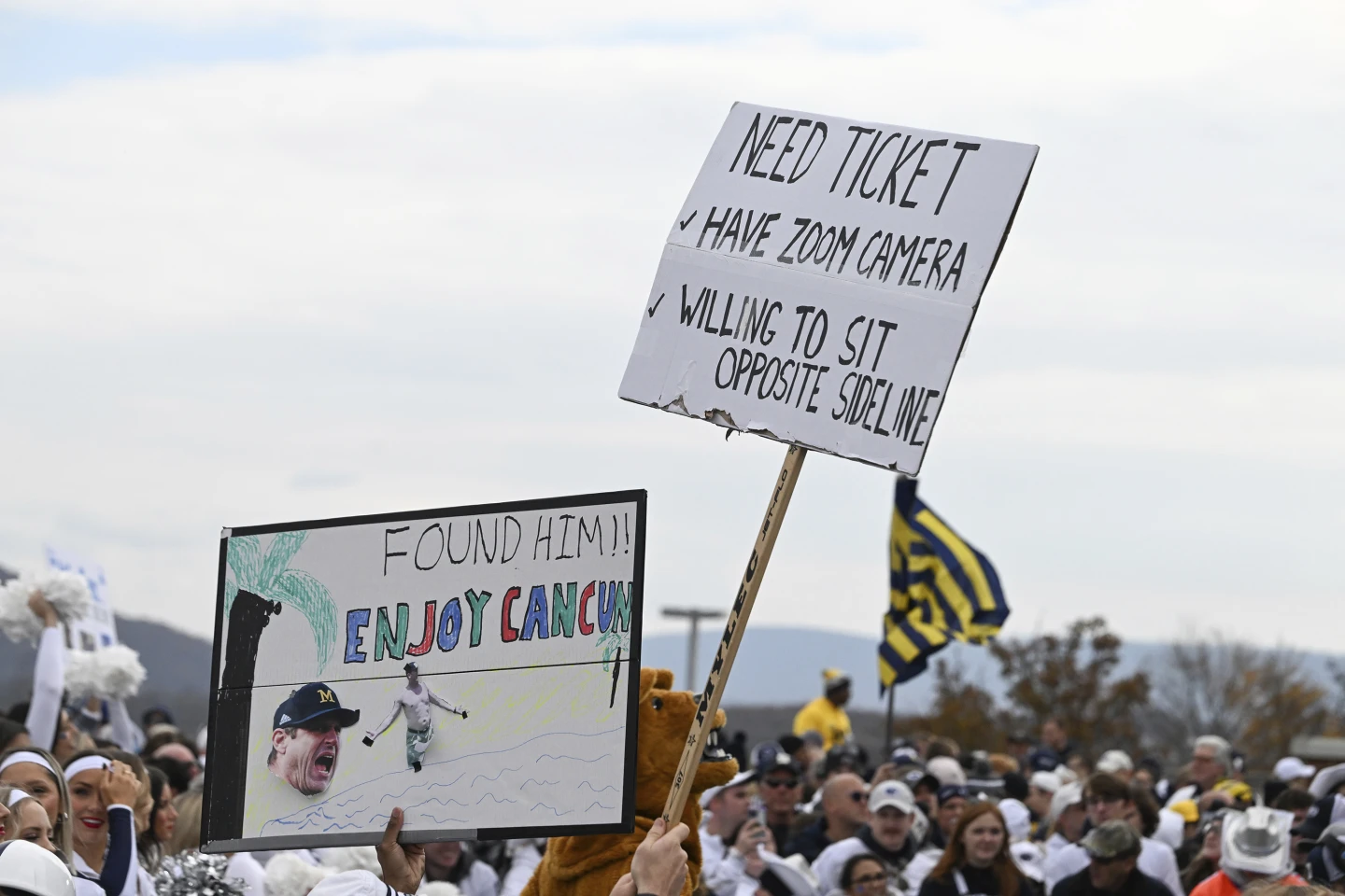 Fans display signs about Michigan head coach Jim Harbaugh outside of Beaver Stadium before an NCAA college football game against Penn State
