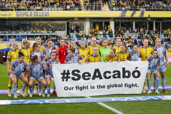 The Swedish and Spanish teams hold a banner reading '#SeAcabó - Our fight is the global fight' before the Women's Nations League soccer match between Sweden and Spain at Gamla Ullevi in Gothenburg, Sweden, Friday Sept. 22, 2023. (Adam Ihse/TT News Agency via AP)
