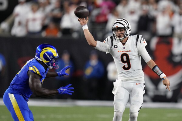 Cincinnati Bengals quarterback Joe Burrow, right, throws over Los Angeles Rams outside linebacker Byron Young (0) during the second half of an NFL football game Monday, Sept. 25, 2023, in Cincinnati. (AP Photo/Michael Conroy)