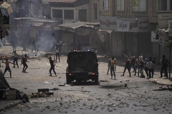 Palestinians clash with Palestinian security forces following an arrest raid against local militants, in the West Bank city of Nablus Tuesday, Sept. 20, 2022. Palestinian security forces on Tuesday exchanged fire with militants in the center of the West Bank's second-largest city, as angry residents pelted an armored jeep with objects and chased it away. One man was reported dead. The incident, sparked by an arrest raid against local militants, marked a rare case of deadly internal Palestinian fighting in the occupied West Bank. (AP Photo/Nasser Nasser)
