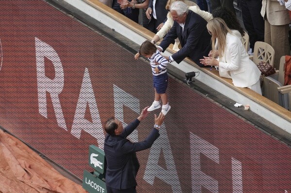 Rafa Nadal abraza a su hijo Rafael Junior durante una ceremonia de despedida en la cancha central Philippe-Chatrier, en el estadio Roland-Garros, en París, el domingo 25 de mayo de 2025. (Foto AP/Christophe Ena)