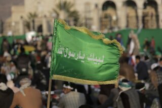 FILE - In this Nov. 9, 2019 file photo, a supporter of Shiite rebels, known as Houthis, holds a banner with Arabic writing that reads, "at your order, oh messenger of Allah," during a celebration of Mawlid al-Nabi the birth of Islam's prophet Muhammad in Sanaa, Yemen. A drastic escalation in fighting between the Saudi-led military coalition and Houthi rebels in Yemen has killed and wounded hundreds of people over the past week, officials and tribal leaders said on Monday, Jan. 27, 2020.   (AP Photo/Hani Mohammed, File)