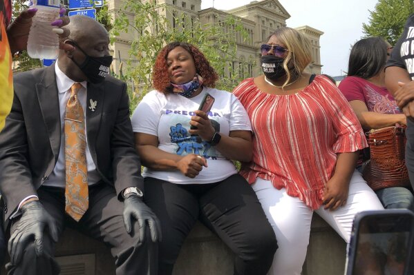 Tamika Palmer, Breonna Taylor's mother, in white beside Attorney Ben Crump, left, speak in Louisville, Ky., after settlement was announced. The city of Louisville will pay $12 million to the family of Breonna Taylor and reform police practices as part of a lawsuit settlement months after Taylor's slaying by police thrust the Black woman's name to the forefront of a national reckoning on race, Mayor Greg Fischer announced Tuesday.(AP Photo/Dylan Lovan)