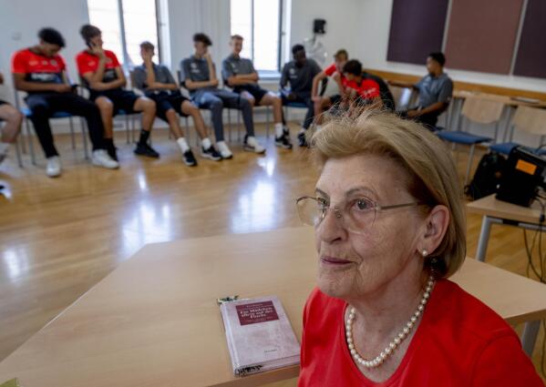 Holocaust survivor Eva Szepesi talks to youth players of Bayern Munich in Nuremberg, Germany, Friday, July 29, 2022. Some of Europe's best young soccer players from the under-17 teams of Chelsea, Bayern Munich, Bologna and other international clubs contest the Walther Bensemann Memorial Tournament in Nuremberg, where they also learn the dangers of intolerance by meeting Holocaust survivors, attending workshops and taking part in excursions. (AP Photo/Michael Probst)