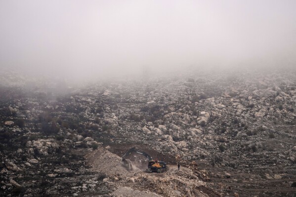 An Israeli bulldozer maneuvers on the buffer zone near the so-called Alpha Line that separates the Israeli-controlled Golan Heights from Syria, viewed from the town of Majdal Shams, Dec. 21, 2024. (AP Photo/Matias Delacroix, File)