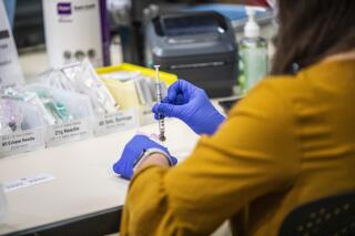 A healthcare worker prepares a Pfizer vaccine dose at a large-scale vaccination site at UNC's Friday Center in Chapel Hill, N.C. Tuesday, Jan. 19 2021. Major hospital systems across North Carolina will soon require workers to get a COVID-19 shot if they want to keep working at the facilities. The decision comes as state health officials warn of a rise in cases fueled by the delta variant. Communities with large unvaccinated populations have been particularly hard hit. The state Healthcare Association said on Thursday, July 22, 2021 that Duke Health, Atrium Health and many UNC Health hospitals will soon compel workers to get vaccinated. (Travis Long/The News & Observer via AP)