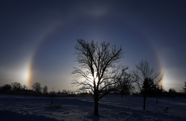 Cães solares são vistos em cada lado do sol no Noelridge Park, no nordeste de Cedar Rapids, Iowa, no domingo, 14 de janeiro de 2024. As ilusões de ótica são causadas pela refração da luz solar por cristais de gelo na atmosfera.  (Jim Slosiarek/The Gazette Via AP)