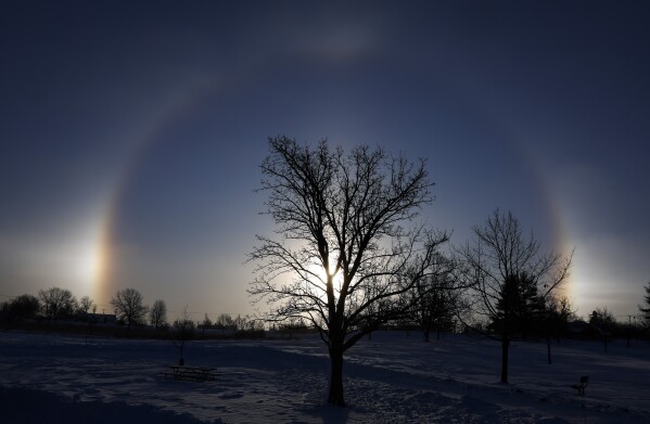 Sun dogs are seen on each side of the sun at Noelridge Park in northeast Cedar Rapids, Iowa, on Sunday, Jan. 14, 2024. The optical illusions are caused by the refraction of sunlight by ice crystals in the atmosphere. (Jim Slosiarek/The Gazette Via AP)