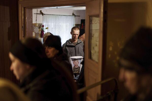 A man holds a photograph of Dmytro Shapovalov, a Ukrainian serviceman, during his funeral ceremony in Yosypivka village, Vinnytsia region, Ukraine, on Friday, June 13, 2025. (AP Photo/Evgeniy Maloletka)